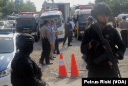 Polisi berjaga saat proses memasukkan jenazah yang disimpan di kontainer ke dalam peti jenazah di mobil ambulance (Foto:VOA/Petrus Riski).