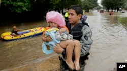A member to the Texas Army National Guard carries Daniel Lopez to dry ground as people evacuate a neighborhood that was inundated after water was released from nearby Addicks Reservoir, Aug. 29, 2017, in Houston, Texas.