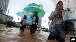 Women wade through a flooded street in Jakarta, Indonesia, January 17, 2013.