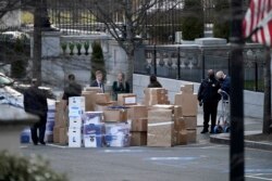 In this Jan. 14, 2021, file photo people wait for a moving van after boxes were moved out of the Eisenhower Executive Office building inside the White House complex in Washington.
