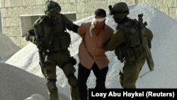 Tentara Israel menangkap seorang Palestina selama operasi militer untuk gerilyawan yang dicari di kota Ramallah, Tepi Barat, 4 Juni 2006. (Foto: REUTERS/Loay Abu Haykel)