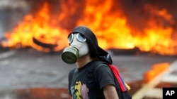 An anti-government protester stands in front of burning barricade on a highway in Caracas, Venezuela, April 24, 2017. 