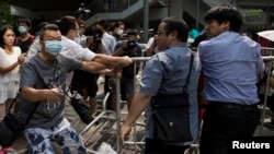ຊາຍຄົນນຶ່ງຈາກຝ່າຍຕໍ່ຕ້ານ ພວກປະທ້ວງ Occupy Central ຫລື ​ເຂົ້າ​ຄອບຄອງ​ໃຈກາງ​ຮົງ​ກົງ (ຊ້າຍ) ຖືຄີມຕັດສາຍລວດ ທີ່ໃຊ້ຕັດສາຍລວດ ທີ່ມັດສິ່ງກີດຂວາງເຂົ້າກັນ ໃນຂະນະທີ່ຝ່າຍປະທ້ວງສອງຄົນພະຍາຍາມ ສະກັດກັ້ນພວກເຂົາ ຢູ່ໃຈກາງເມືອງ ຮົງກົງ, ວັນທີ 13 ຕຸລາ 2014.