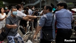 An anti-Occupy Central protester (L) holds pliers as he cuts cable ties at barricades setup as road blocks by protesters in Hong Kong, Oct. 13, 2014.