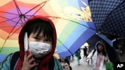 A South Korean student holding an umbrella talks on his mobile phone as he goes to his home amid fears that the rain may contain radioactive materials from the crippled nuclear reactors in Japan at Midong elementary school in Seoul, April 7, 2011