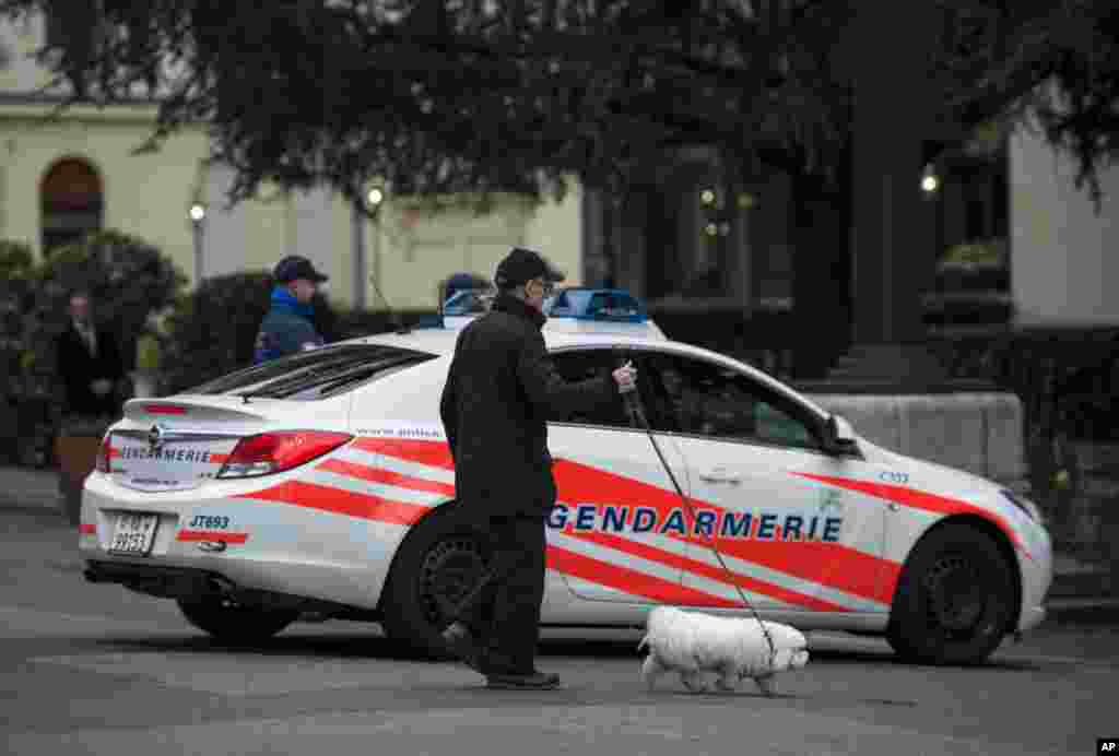 A man walks a dog past a police vehicle near the Beau Rivage Palace Hotel in Lausanne, April 2, 2015,.