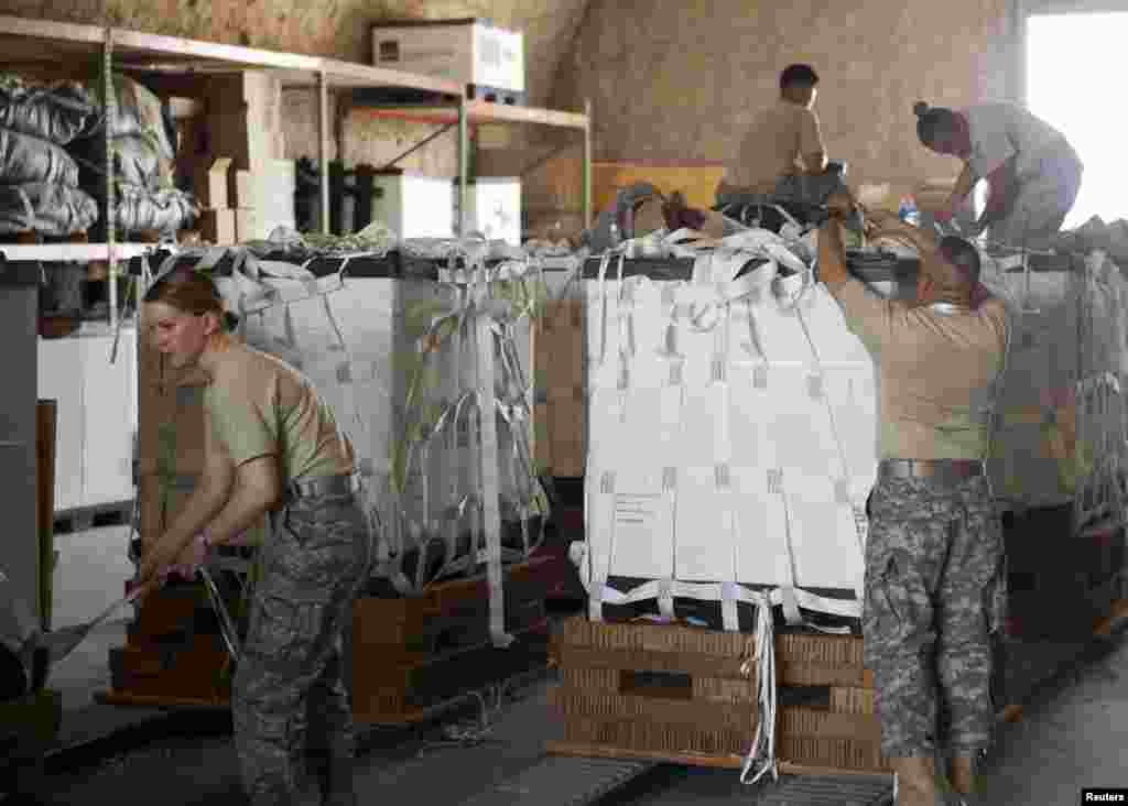 Service member volunteers prepare a pallet of food and water before loading it onto aircraft for air drops near Sinjar, Iraq, Aug. 11, 2014. (U.S. Department of Defense)