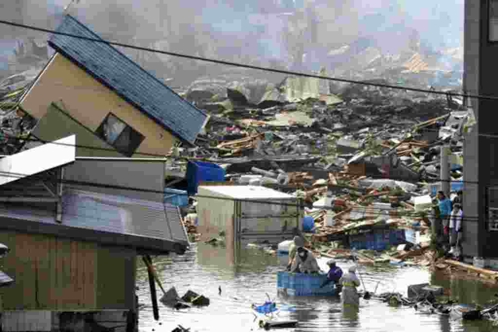 People, in a floating container, are rescued from a building following an earthquake and tsunami in Miyagi Prefecture, northeastern Japan March 12, 2011. Japan confronted devastation along its northeastern coast on Saturday, with fires raging and parts of