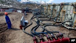 FILE - A worker helps monitor water pumping pressure and temperature, at a hydraulic fracturing and extraction site, outside Rifle, in western Colorado, March 29, 2013. 