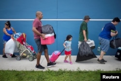 Residents carry their belongings into a shelter ahead of the landfall of Hurricane Irma in Estero, Fla., Sept. 9, 2017.