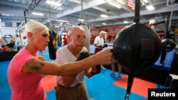 Parkinson's patient Jim Coppula gets some pointers from his daughter Ellen as he works out on a bag during his Rock Steady Boxing class in Costa Mesa, California September 18, 2013. 