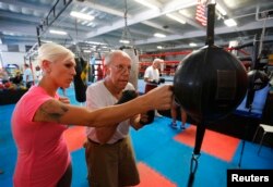 FILE - Parkinson's patient Jim Coppula gets some pointers from his daughter Ellen as he works out on a bag during his Rock Steady Boxing class in Costa Mesa, California, Sept. 18, 2013.