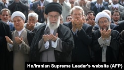 FILE - A handout picture released by the official website of the Iranian supreme leader, Ayatollah Ali Khamenei, shows him, center, leading Eid al-Fitr prayers, with Iranian President Hassan Rouhani at far right, at Tehran's Grand Mosalla, July 18, 2015.