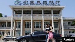 资料照片: 2013年6月27日行人经过北京民间资本设立的全国性股份制商业银行民生银行