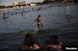 A boy runs with a water pistol at an artificial pond known as piscinao, or big pool, in the northern suburbs of Rio de Janeiro, Brazil, Jan. 8, 2017.