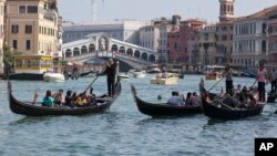 FILE - Tourists tour the Grand Canal on traditional Gondola Venetian boats, in Venice, Italy, Sept. 28, 2014.