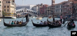 FILE - Tourists tour the Grand Canal on traditional Gondola Venetian boats, in Venice, Italy, Sept. 28, 2014.