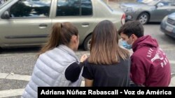 Tres jóvenes revisan sus teléfonos celulares en una plaza de Caracas