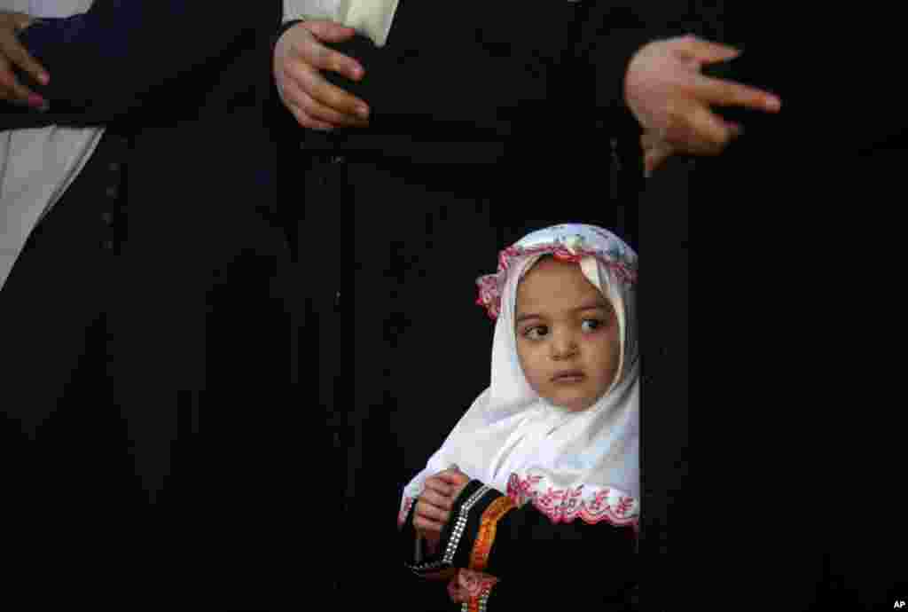 A young Palestinian girl attends prayers on the first day of Eid al-Adha at Al-Yarmouk stadium in Gaza City, Oct. 15, 2013.