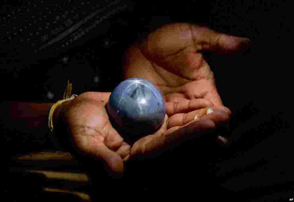 A Sri Lankan displays a star blue sapphire, claimed to be the world&#39;s biggest star blue sapphire, in Colombo, Sri Lanka. The Gemological institute of Colombo, a local gem industry body, has certified that the gem weighs 1,404.49 carats (281 grams).