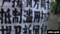 2013年1月9日星期三, 广州市《南方周末》总部大楼前抗议人士展示反对《南方周末》新年献词遭受删改的标语(美国之音截图)