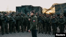 Poland's Prime Minister Mateusz Morawiecki addresses service members near the frontier, as hundreds of migrants gather on the Belarusian side of the border with Poland in an attempt to cross it, near Kuznica Bialostocka, Poland, Nov. 9, 2021. 