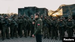 Poland's Prime Minister Mateusz Morawiecki addresses service members near the frontier, as hundreds of migrants gather on the Belarusian side of the border with Poland in an attempt to cross it, near Kuznica Bialostocka, Poland, Nov. 9, 2021. 