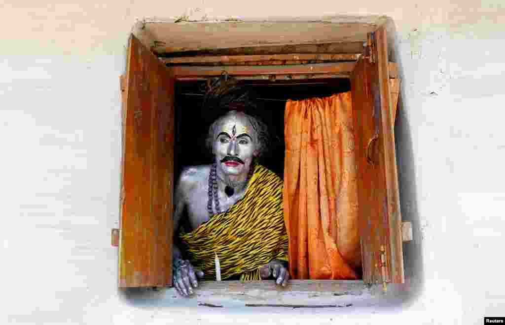 A devotee, dressed as Hindu God Shiva, looks out from a window as he waits to perform during the annual Shiva Gajan religious festival on the outskirts of Agartala, India.