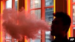 FILE - A patron exhales vapor from an e-cigarette at the Henley Vaporium in New York