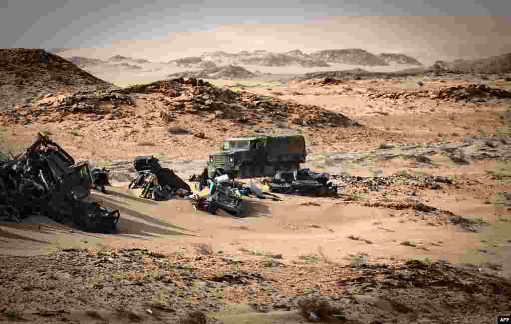 A Moroccan army vehicle drives past car wreckages in Guerguerat located in the Western Sahara, after the intervention of the royal Moroccan armed forces in the area, Nov. 24, 2020.