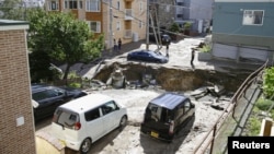 FILE - People look at an area damaged by an earthquake in Sapporo in Japan's northern island of Hokkaido, Japan, in this photo taken by Kyodo, Sept. 6, 2018. 