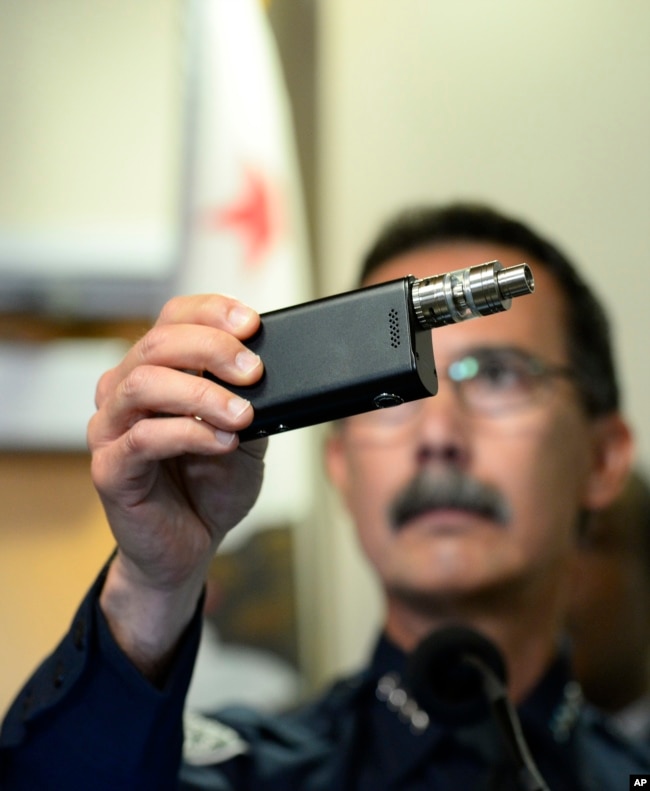 FILE - El Cajon Police Department Capt. Jeffery Davis holds up a vape device similar to the one that they claim that Alfred Olango was holding when he was shot, in El Cajon, Calif., Sept. 30, 2016.