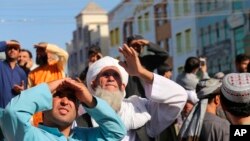 People look up at a dead body hanged by the Taliban from a crane in the main square of Herat city in western Afghanistan, on Sept. 25, 2021. 