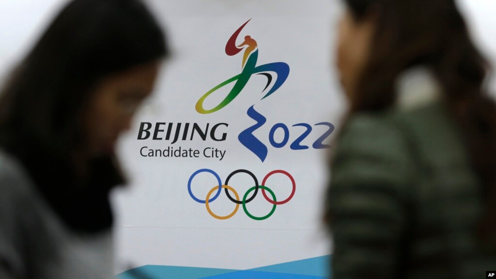 在北京申请主办2022冬奥会海报前交谈的记者们（美联社图片）(photo:VOA)