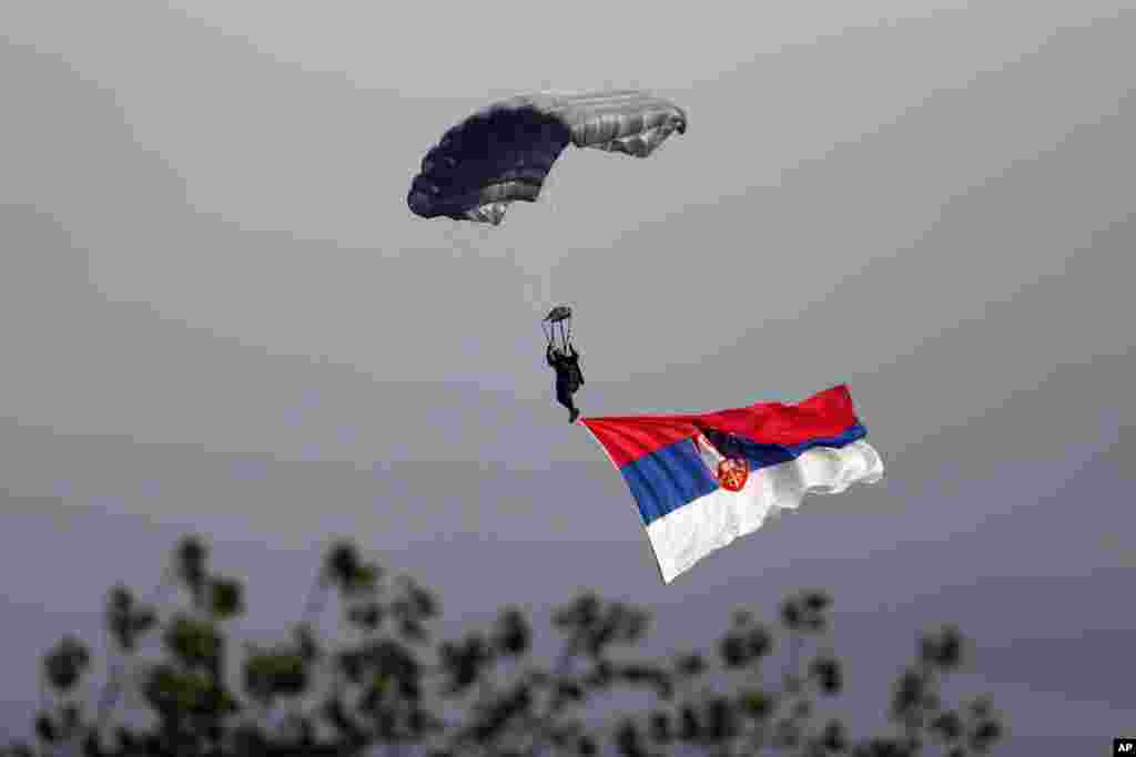 A Serbian army paratrooper descends during a military parade in Belgrade. Waving Russian and Serbian flags and displaying banners “Thank You Russia,” tens of thousands came to see the parade in Belgrade attended by Vladimir Putin, which marked the 70th anniversary of the liberation of the Serbian capital from the Nazi German occupation by the Red Army and Communist Yugoslav Partisans.