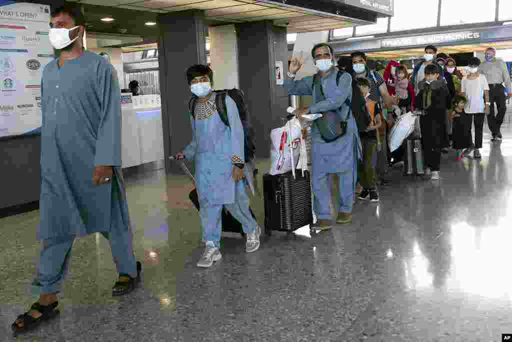 Families evacuated from Kabul, Afghanistan, walk through the airport before boarding a bus after they arrived at Washington Dulles International Airport, in Chantilly, Virginia.