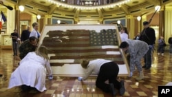 Workers carry the 34-star U.S. national flag of the 15th Iowa Infantry 