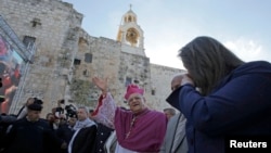 The Latin Patriarch of Jerusalem Fouad Twal waves upon his arrival to attend Christmas celebrations in the West Bank town of Bethlehem, Dec. 24, 2014.