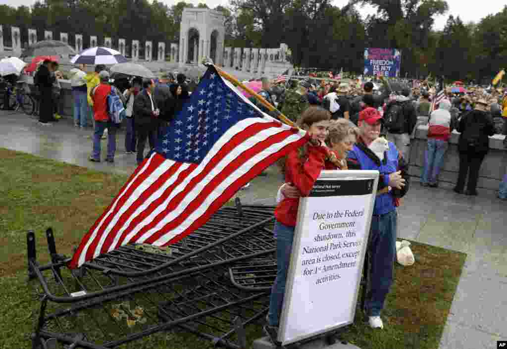 Kaylee, Sherry y Michael Cantrell posan para la foto con una pancarta tras remover las barricadas del Monumento en honor a los combatientes de la Segunda Guerra Mundial en Washington.