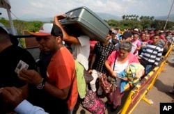 FILE - Fleeing political and economic instability in their homeland, Venezuelans cross the International Simon Bolivar bridge into Colombia, Feb. 21, 2018.