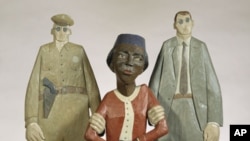 In this wooden sculpture by Marshall D. Rumbaugh, Rosa Parks is held by two policemen. Parks was arrested after refusing to give up her seat to a white male bus rider in Montgomery, Alabama.