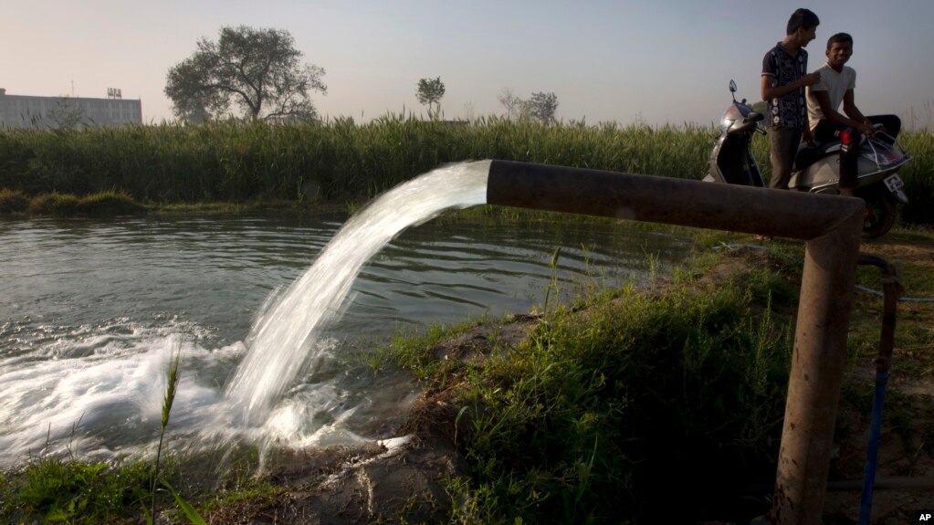 En India, dos personas conversan mientras extraen agua de un pozo para su cosecha en el Día Mundial del Agua, en las afueras de Nueva Delhi, India, el miércoles, 22 de marzo, de 2017. 