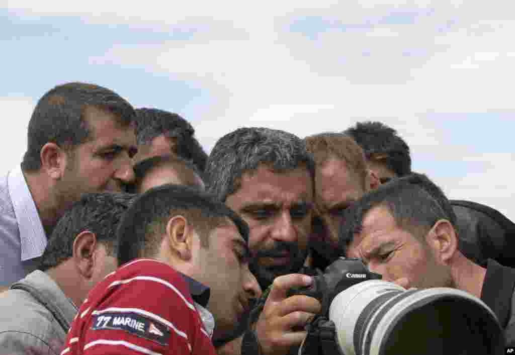 Turkish Kurds watch the fighting between Islamic militants and Kurdish forces to the west of Kobani, Syria, through a photographer&#39;s camera at the Turkey-Syria border near Suruc, Turkey, Sept. 30, 2014. 