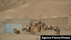 This picture taken on October 15, 2021 shows children filling jerrycans with water from a water storage in Bala Murghab district of Badghis province.