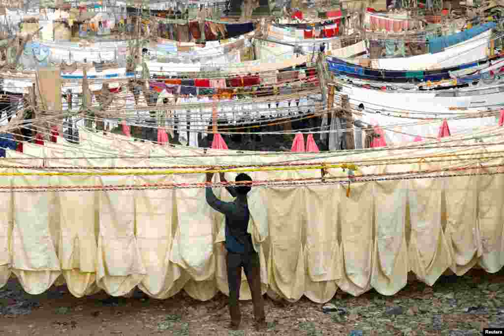 A laundry man removes chair covers from a rope after a wash and dry at a Dhobi Ghat (washing place) in Karachi, Pakistan.