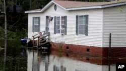 Džo Vigins sedi na tremu svoje kuće dok ga okružuje vode nakon što je uragan Florens protutnjao ostrvom Emerald, Severna Karolina, 16. septembra 2018.