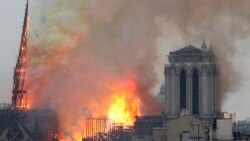 Flames rise from Notre Dame cathedral as it burns in Paris, Monday, April 15, 2019. Massive plumes of yellow brown smoke is filling the air above Notre Dame Cathedral and ash is falling on tourists and others around the island that marks the center of Par