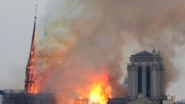 Flames rise from Notre Dame cathedral as it burns in Paris, Monday, April 15, 2019. Massive plumes of yellow brown smoke is filling the air above Notre Dame Cathedral and ash is falling on tourists and others around the island that marks the center of Par