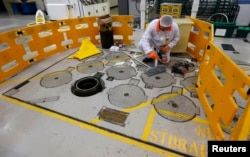 FILE - An environmental safety monitor carries out contamination checks in the charge hall inside EDF Energy's Hinkley Point B nuclear power station in Bridgwater, southwest England, December 13, 2012.