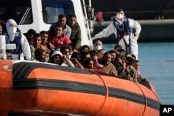 FILE - Migrants and refugees enter in the port of Roccella Jonica, Calabria region, southern Italy, Nov. 14, 2021.